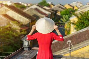 gelukkig vrouw vervelend oa dai Vietnamees jurk, reiziger bezienswaardigheden bekijken visie Bij op het dak in Hoi een oude dorp. mijlpaal en populair voor toerist attracties. Vietnam en zuidoosten reizen concept foto