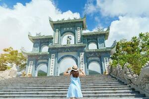 vrouw reiziger bezoekende Bij linh ung pagode tempel, vertaling van Chinese karakter. toerist met blauw jurk en hoed op reis in da nang stad. Vietnam en zuidoosten Azië reizen concept foto