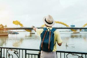 Mens reiziger met rugzak bezoekende in da nang. toerist bezienswaardigheden bekijken de rivier- visie met draak brug Bij liefde slot brug. mijlpaal en populair. Vietnam en zuidoosten Azië reizen concept foto