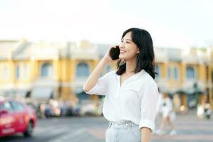 portret mooi jong Aziatisch vrouw met slim mobiel telefoon in de omgeving van buitenshuis straat visie in een zomer dag foto