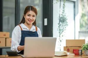 portret van aziatische jonge vrouw mkb werkend met een doos thuis de werkplek. start-up kleine ondernemer, kleine ondernemer mkb of freelance bedrijf online en leveringsconcept. foto