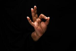 Aziatisch mannetje donker huid single hand- vuist vinger Aan zwart achtergrond OK vinger teken foto