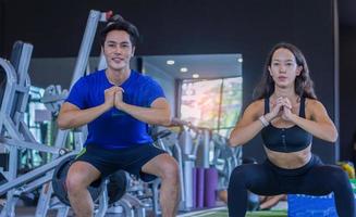 mooie aziatische vrouw oefent in een sportschool met een personal trainer knappe man fitness foto