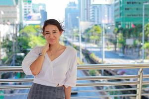 portret van een mooie vrouw die in een stadsgebouw staat en een gelukkig stedelijke levensstijl glimlacht foto