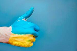 een man's hand- geschilderd in de kleur van de vlag van Oekraïne met een vinger verheven omhoog. foto