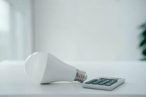 energie besparing concept. rekenmachine met licht lamp . opslaan elektriciteit. foto