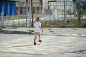 een weinig jongen is rennen langs de zebrapad. de kind loopt langs de weg naar kleuterschool en school. zebra wandelen in de stad. concept van voetgangers voorbijgaan zebrapad foto