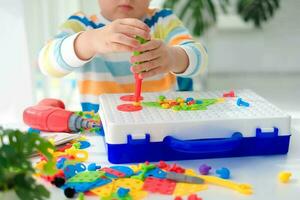 weinig jongen spelen reeks met een schroevedraaier en een oefening, en schroeven en onderdelen . de kind Toneelstukken bouwer met een speelgoed- boren naar ontwikkelen verbeelding en motor vaardigheden. leerzaam logica speelgoed voor kinderen. foto