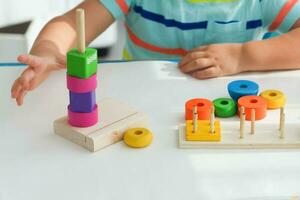 een weinig jongen Toneelstukken met houten speelgoed en bouwt een toren. leerzaam logica speelgoed voor kinderen. montessori spellen voor kind ontwikkeling. kinderen houten speelgoed. foto