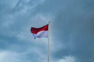 Indonesisch vlag fladderend met wolken achtergrond - symbool van nationaal trots en kalmte foto