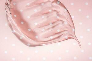transparant hyaluronzuur gel Aan een roze polka dots achtergrond. foto