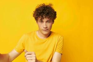 portret van een jong gekruld Mens vervelend elegant geel t-shirt poseren geel achtergrond ongewijzigd foto