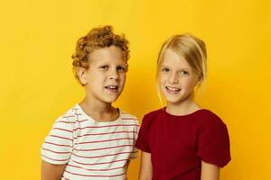 portret van schattig kinderen staand kant door kant poseren kinderjaren emoties geel achtergrond foto