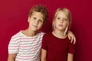 klein kinderen emoties staan kant door kant in elke dag kleren rood achtergrond ongewijzigd foto