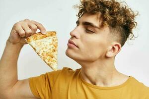 knap jong Mens in een geel t-shirt aan het eten pizza levensstijl ongewijzigd foto