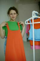 grappig meisje strijken kleren Aan een hanger garderobe licht achtergrond ongewijzigd foto