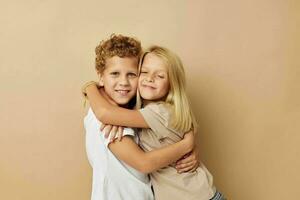 jongen en meisje in t-shirts knuffels beige achtergrond vriendschap foto