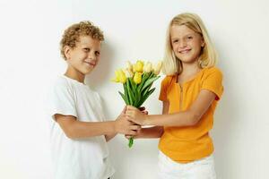 jongen en meisje met een boeket van bloemen geschenk verjaardag vakantie kinderjaren licht achtergrond foto