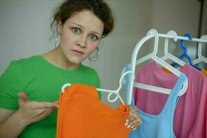 mooi vrouw groen t-shirts in de buurt kleren hangers geïsoleerd achtergronden ongewijzigd foto