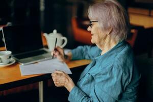 gelukkig senior vrouw zittend in een cafe met een kop van koffie en een laptop gepensioneerd vrouw chatten ongewijzigd foto