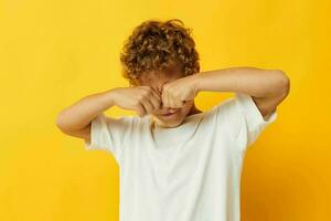 jongen met gekruld haar- kinderjaren poseren geel achtergrond foto