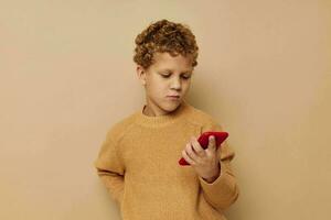 jongen in een trui met een telefoon in zijn handen technologie beige achtergrond foto