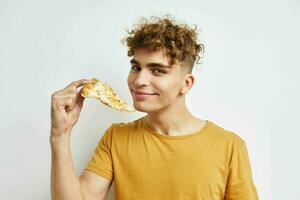 knap vent in een geel t-shirt aan het eten pizza geïsoleerd achtergrond foto