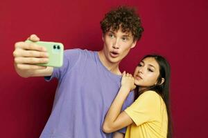 mooi hoor vent en meisje in kleurrijk t-shirts met een telefoon rood achtergrond foto