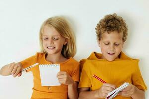 portret van schattig liggen Aan de verdieping met blocnotes en potloden geïsoleerd achtergrond ongewijzigd foto