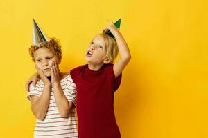 portret van schattig kinderen in gewoontjes kleren met petten Aan de hoofd Aan gekleurde achtergrond foto