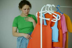 mooi vrouw strijken kleren Aan een hanger garderobe licht achtergrond ongewijzigd foto