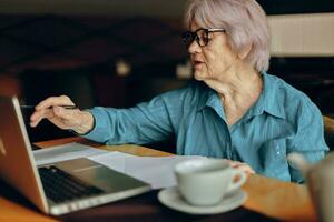 mooi volwassen senior vrouw werken in voorkant van laptop toezicht houden op zittend gepensioneerd vrouw chatten ongewijzigd foto