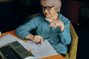 gelukkig senior vrouw zittend in een cafe met een kop van koffie en een laptop gepensioneerd vrouw chatten ongewijzigd foto