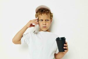 foto portret gekruld weinig jongen wat soort van drinken is de telefoon in hand- communicatie geïsoleerd achtergrond ongewijzigd