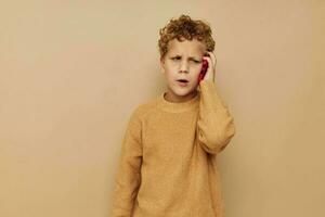 jongen in een trui met een telefoon in zijn handen technologie beige achtergrond foto