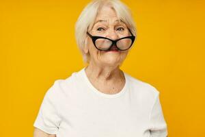 portret van een oud vriendelijk vrouw in een wit t-shirt draagt bril geïsoleerd achtergrond foto
