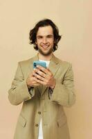 aantrekkelijk Mens met een telefoon in hand- beige pak elegant stijl levensstijl ongewijzigd foto