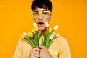 een jong Mens in geel bril met een boeket van bloemen vakantie ongewijzigd foto