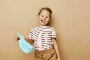 portret van gelukkig glimlachen kind meisje in blauw petten gestreept t-shirt emoties beige achtergrond foto