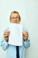 foto van gepensioneerd oud Mens Holding documenten met een vel van papier licht achtergrond