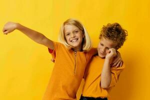 vrolijk kinderen in geel t-shirts staand kant door kant kinderjaren emoties geel achtergrond foto