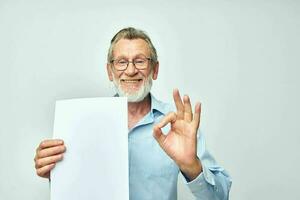 portret ouderen Mens Holding een vel van papier kopie-ruimte poseren bijgesneden visie foto