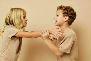 weinig jongen en meisje in beige t-shirts poseren voor pret kinderjaren ongewijzigd foto