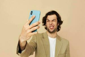 Mens in een pak poseren emoties op zoek Bij de telefoon beige achtergrond foto