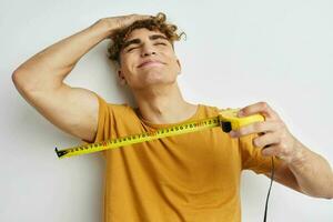 knap jong Mens meten plakband meten in geel t-shirt licht achtergrond foto