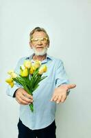 oud Mens in een blauw overhemd met een boeket van bloemen licht achtergrond foto