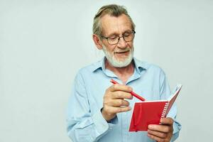 senior grijs haar Mens met rood notitieboekje en pen licht achtergrond foto