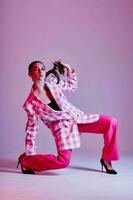 portret van mooi jong vrouw luxe kleding mode plaid blazer roze achtergrond ongewijzigd foto