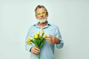 oud Mens geel boeket van bloemen poseren geïsoleerd achtergrond foto