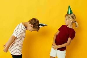 schattig peuter- kinderen vakantie pret met petten Aan uw hoofd geel achtergrond foto